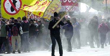 A protester hurls a stick towards riot police during clashes in an anti-war demonstration outside the US embassy in Athens. Photograph: AP