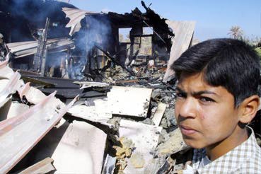 Iraqi boy in front of his burning house