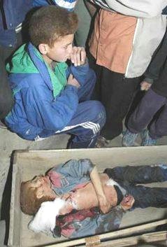 An Iraqi boy sits near the body of his brother